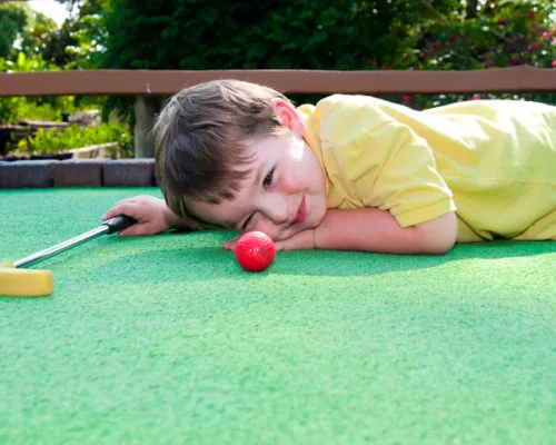 Playing Mini Golf Young boy plays mini golf on putt putt course