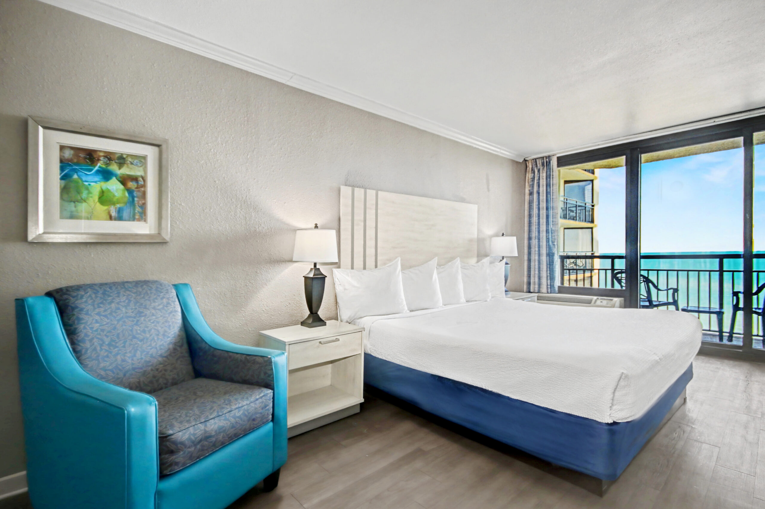 Features 1 king bed, 1 bathroom, a small refrigerator, microwave, and a private balcony with a partial ocean view.
